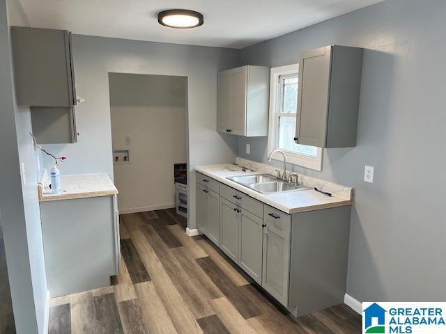 kitchen with dark hardwood / wood-style flooring, gray cabinetry, and sink