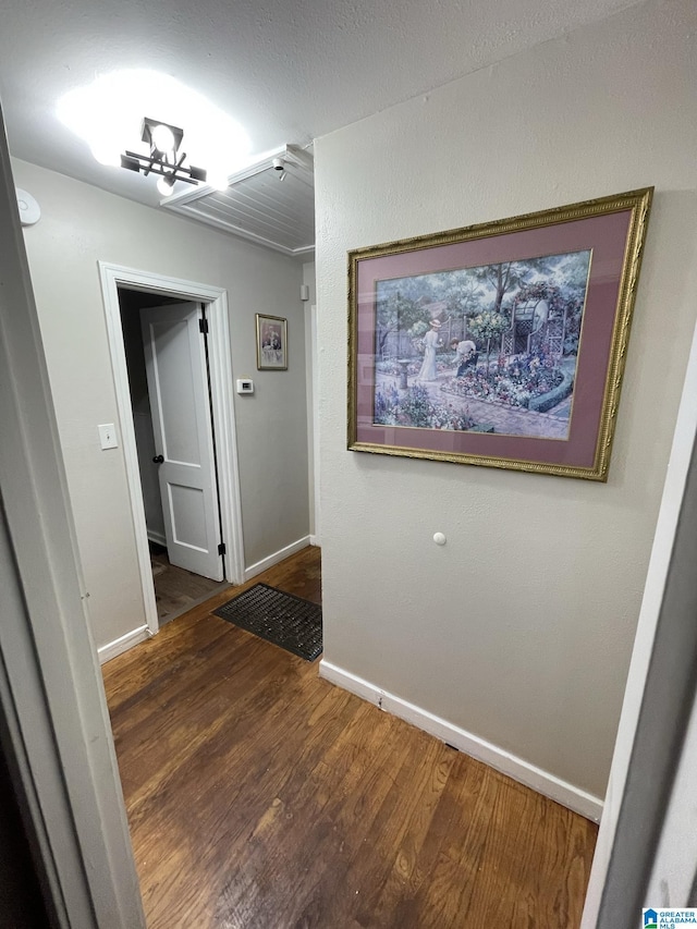 hall with dark wood-type flooring and a chandelier