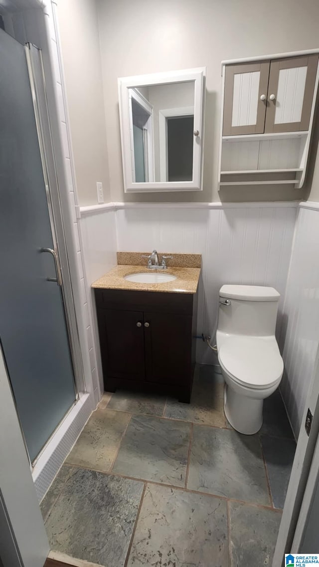 bathroom featuring vanity, toilet, and an enclosed shower