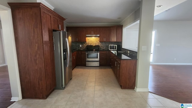 kitchen with decorative backsplash, light tile patterned floors, stainless steel appliances, and dark stone counters