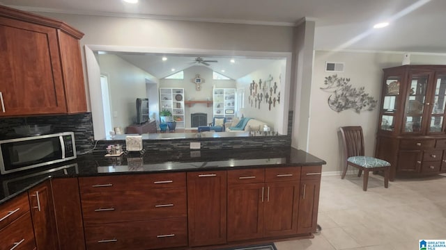 kitchen featuring lofted ceiling, backsplash, dark stone counters, ceiling fan, and light tile patterned floors