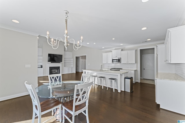 dining area featuring crown molding, dark hardwood / wood-style flooring, sink, and a notable chandelier