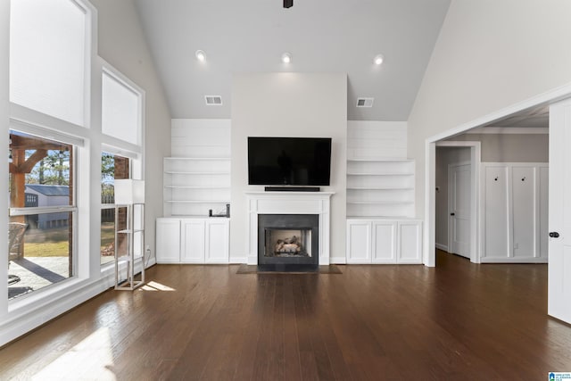 unfurnished living room featuring built in shelves, dark wood-type flooring, and high vaulted ceiling