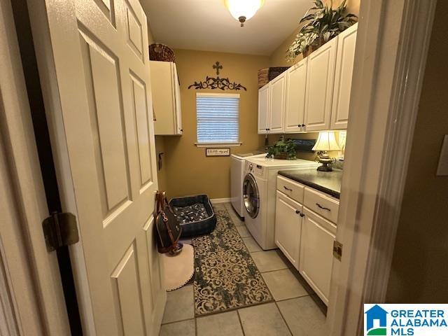 laundry room featuring light tile patterned flooring, cabinets, and washing machine and dryer