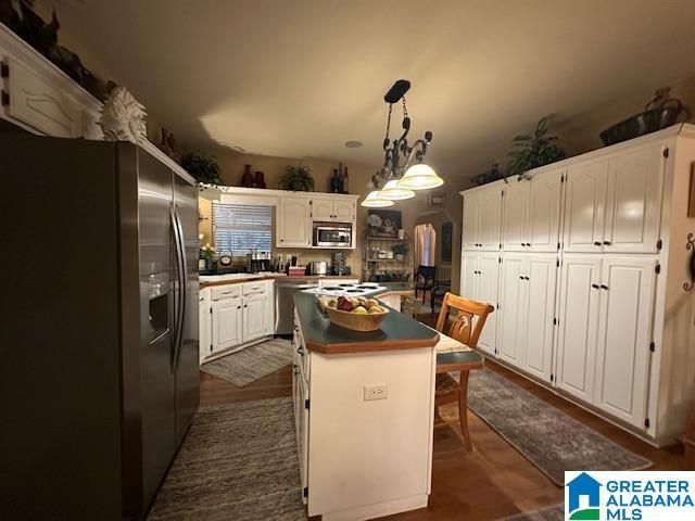 kitchen featuring a center island, white cabinets, hanging light fixtures, dark hardwood / wood-style floors, and stainless steel appliances