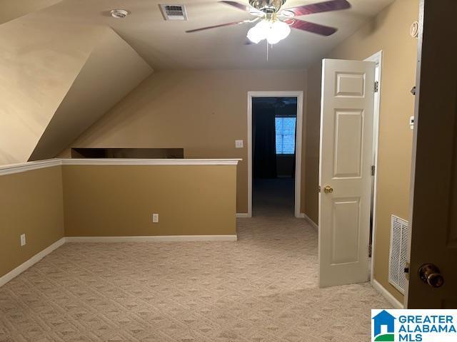 additional living space featuring light carpet, ceiling fan, and vaulted ceiling