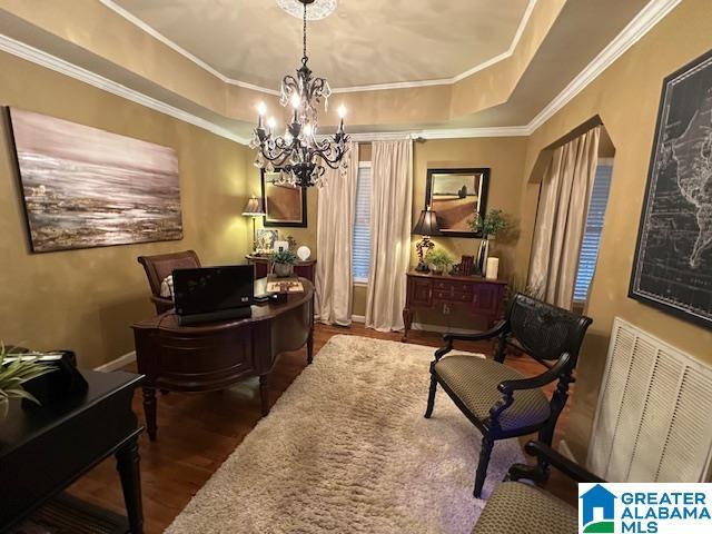 home office featuring dark hardwood / wood-style floors, ornamental molding, a tray ceiling, and a chandelier