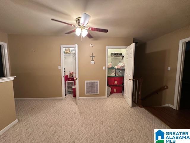 interior space featuring ceiling fan, light colored carpet, and a spacious closet