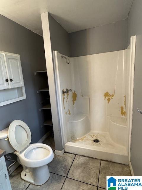 bathroom featuring a shower, vanity, toilet, and tile patterned flooring