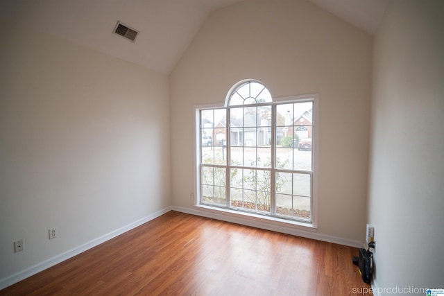 spare room featuring high vaulted ceiling and light hardwood / wood-style flooring