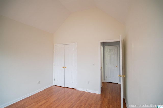 unfurnished bedroom with a closet, high vaulted ceiling, and hardwood / wood-style flooring