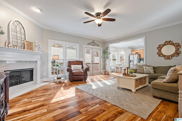 living room with ceiling fan, french doors, crown molding, and light hardwood / wood-style flooring