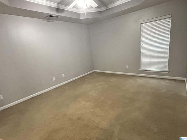 empty room with a raised ceiling, crown molding, carpet, and ceiling fan