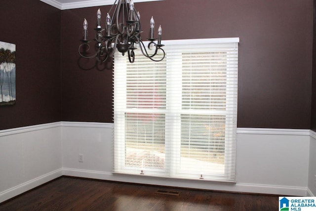 unfurnished dining area featuring dark hardwood / wood-style flooring, ornamental molding, and a chandelier