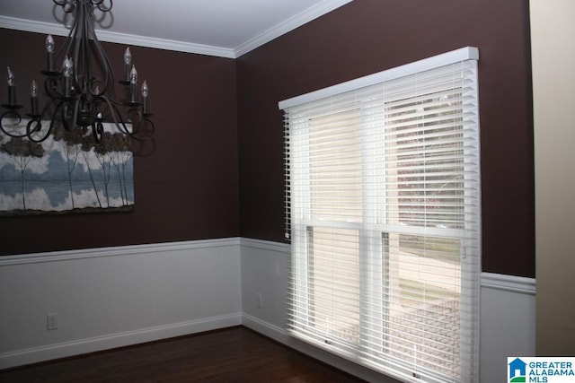 unfurnished dining area with dark hardwood / wood-style floors, ornamental molding, and a chandelier