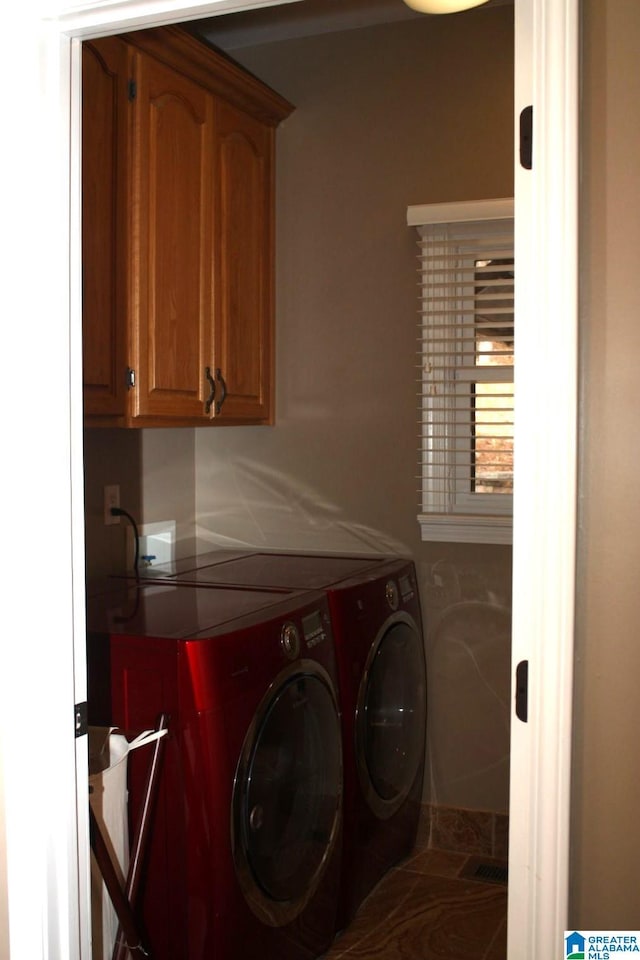 clothes washing area with washer and clothes dryer and cabinets