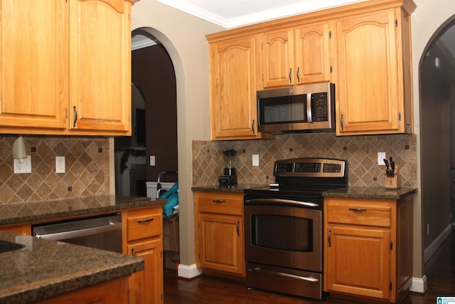 kitchen featuring backsplash, dark hardwood / wood-style floors, ornamental molding, and stainless steel appliances