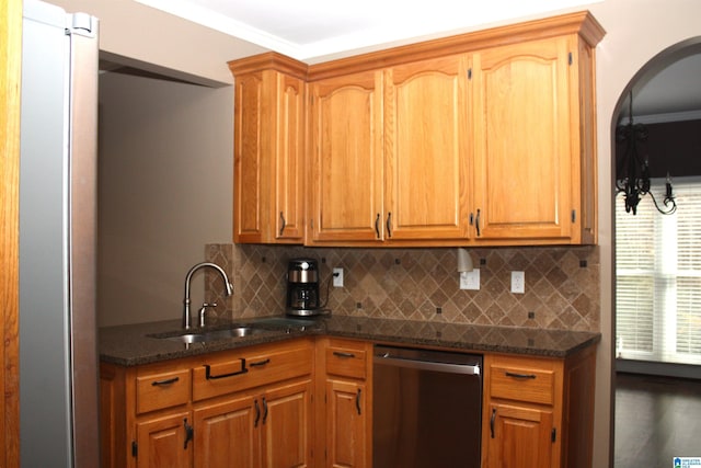 kitchen featuring dishwasher, sink, crown molding, dark stone countertops, and tasteful backsplash