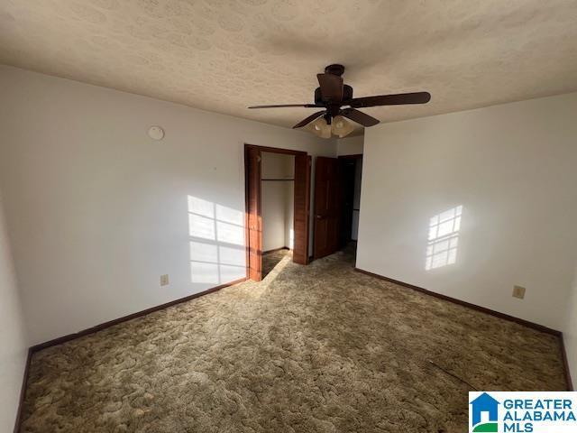 unfurnished bedroom with a textured ceiling, carpet floors, and ceiling fan