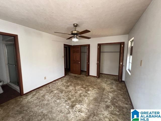 unfurnished bedroom with multiple closets, ceiling fan, and a textured ceiling