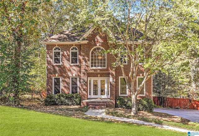 english style home with a front yard and french doors