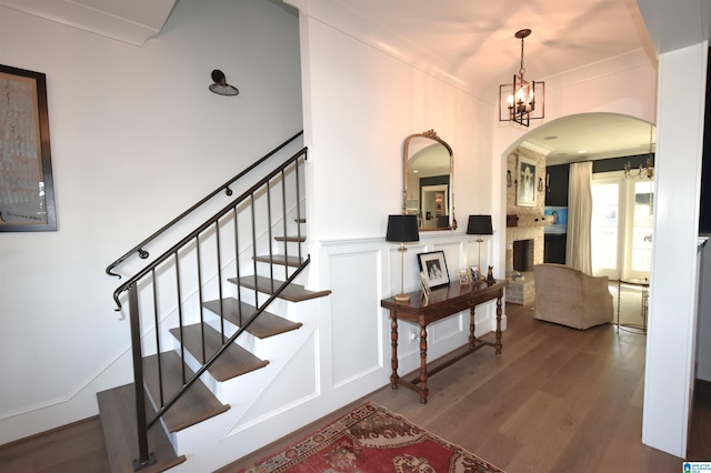 staircase featuring hardwood / wood-style floors, a chandelier, and ornamental molding