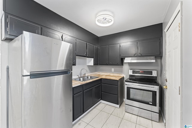 kitchen featuring sink, light tile patterned floors, stainless steel appliances, and wooden counters