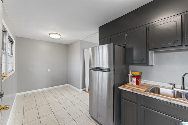 kitchen with stainless steel refrigerator, sink, and light tile patterned flooring