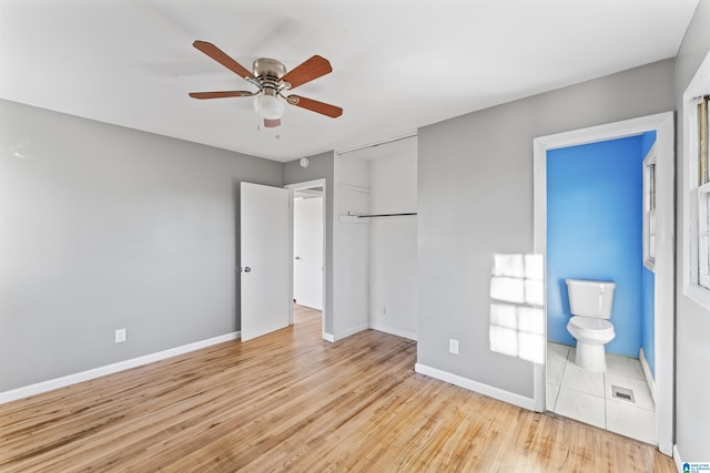 unfurnished bedroom featuring light hardwood / wood-style flooring, ensuite bath, and ceiling fan