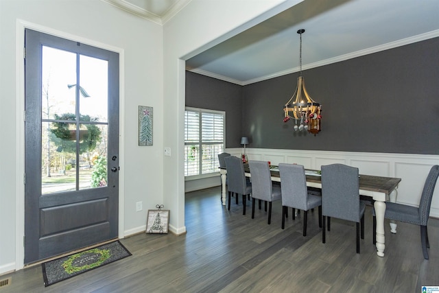 dining space with a chandelier, ornamental molding, and dark wood-type flooring