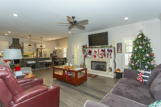 living room with hardwood / wood-style floors, ceiling fan with notable chandelier, and crown molding