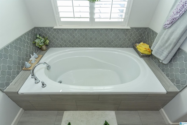 bathroom with a relaxing tiled tub and plenty of natural light