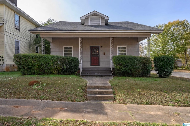 bungalow-style home with covered porch and a front yard