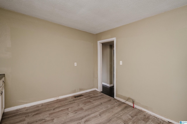 unfurnished room featuring a textured ceiling and light hardwood / wood-style flooring