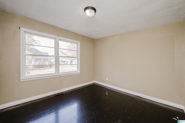 empty room with hardwood / wood-style floors and a textured ceiling