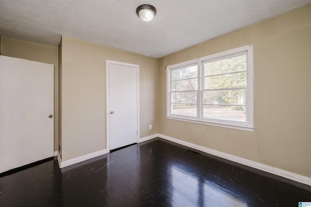 unfurnished room featuring dark hardwood / wood-style flooring and a textured ceiling