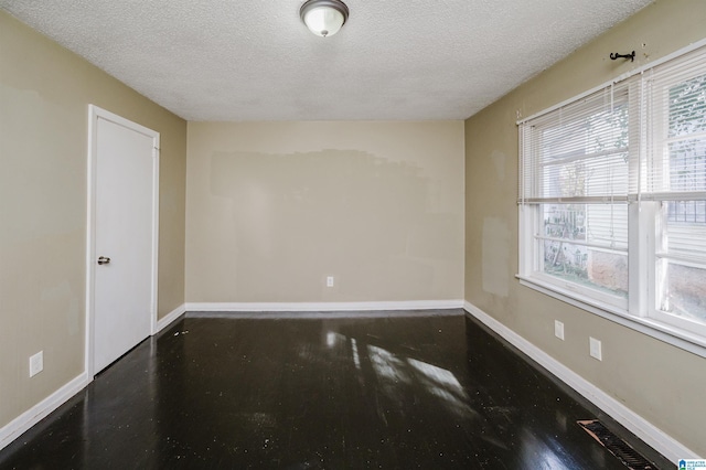 unfurnished room with a textured ceiling and a wealth of natural light