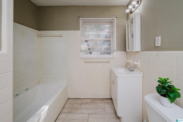 bathroom with vanity, tile patterned floors, toilet, tile walls, and a textured ceiling