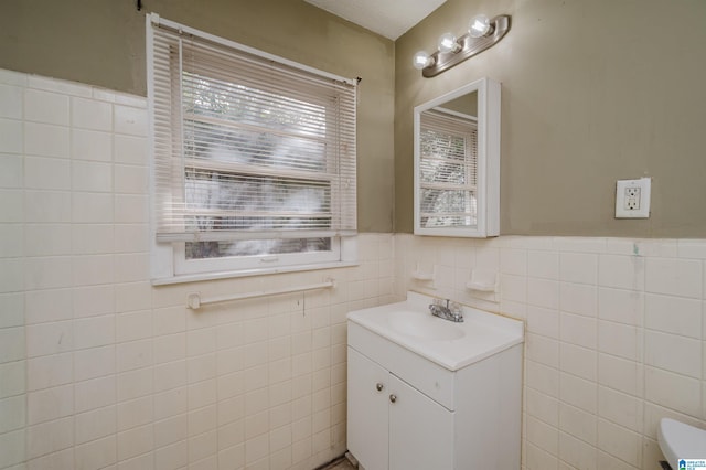 bathroom with vanity, toilet, and tile walls