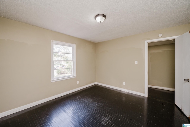 unfurnished room with a textured ceiling and dark hardwood / wood-style floors