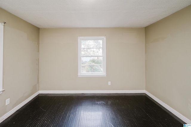 empty room featuring a textured ceiling and dark wood-type flooring