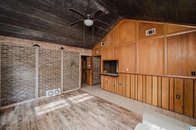 unfurnished living room with ceiling fan, wooden ceiling, brick wall, lofted ceiling, and wooden walls