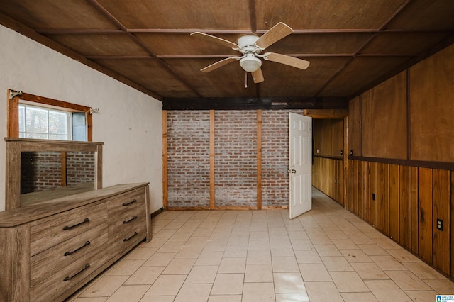 interior space with ceiling fan, wood walls, wood ceiling, and brick wall