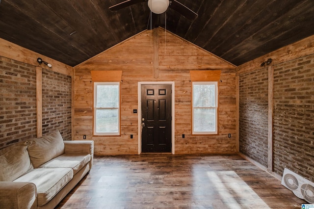 unfurnished living room with hardwood / wood-style floors, plenty of natural light, wood walls, and vaulted ceiling