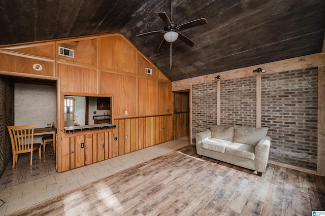 unfurnished living room featuring light wood-type flooring, wooden ceiling, wooden walls, and vaulted ceiling