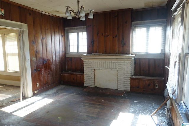 unfurnished living room with wooden walls, a fireplace, and a chandelier