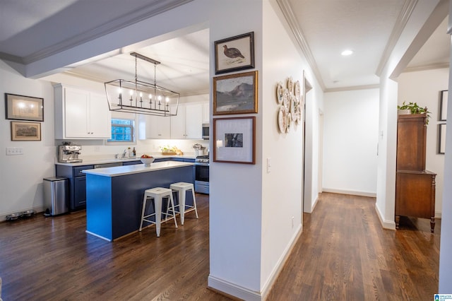 kitchen featuring dark wood-type flooring, white cabinets, hanging light fixtures, a kitchen island, and a breakfast bar area