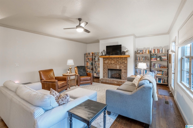 living room featuring dark hardwood / wood-style flooring, a brick fireplace, ceiling fan, and crown molding