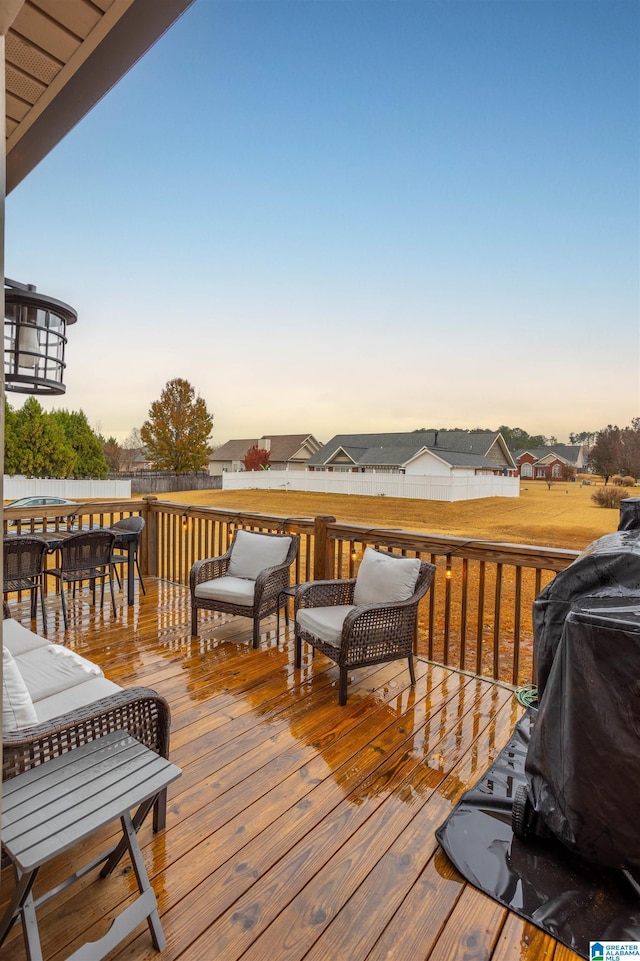 deck at dusk featuring a grill