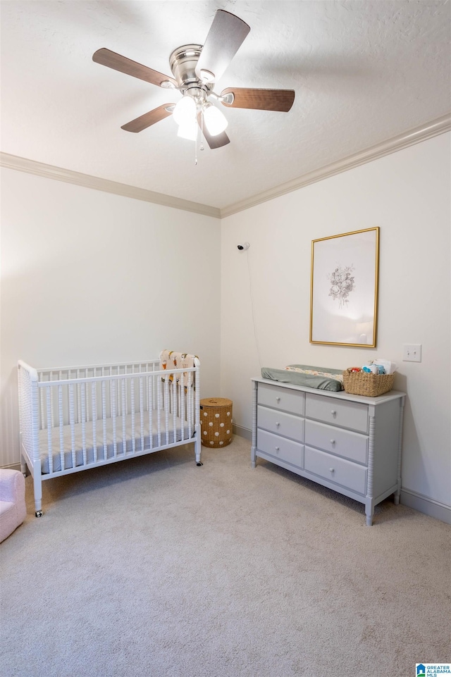 unfurnished bedroom featuring ceiling fan, light carpet, a crib, and ornamental molding